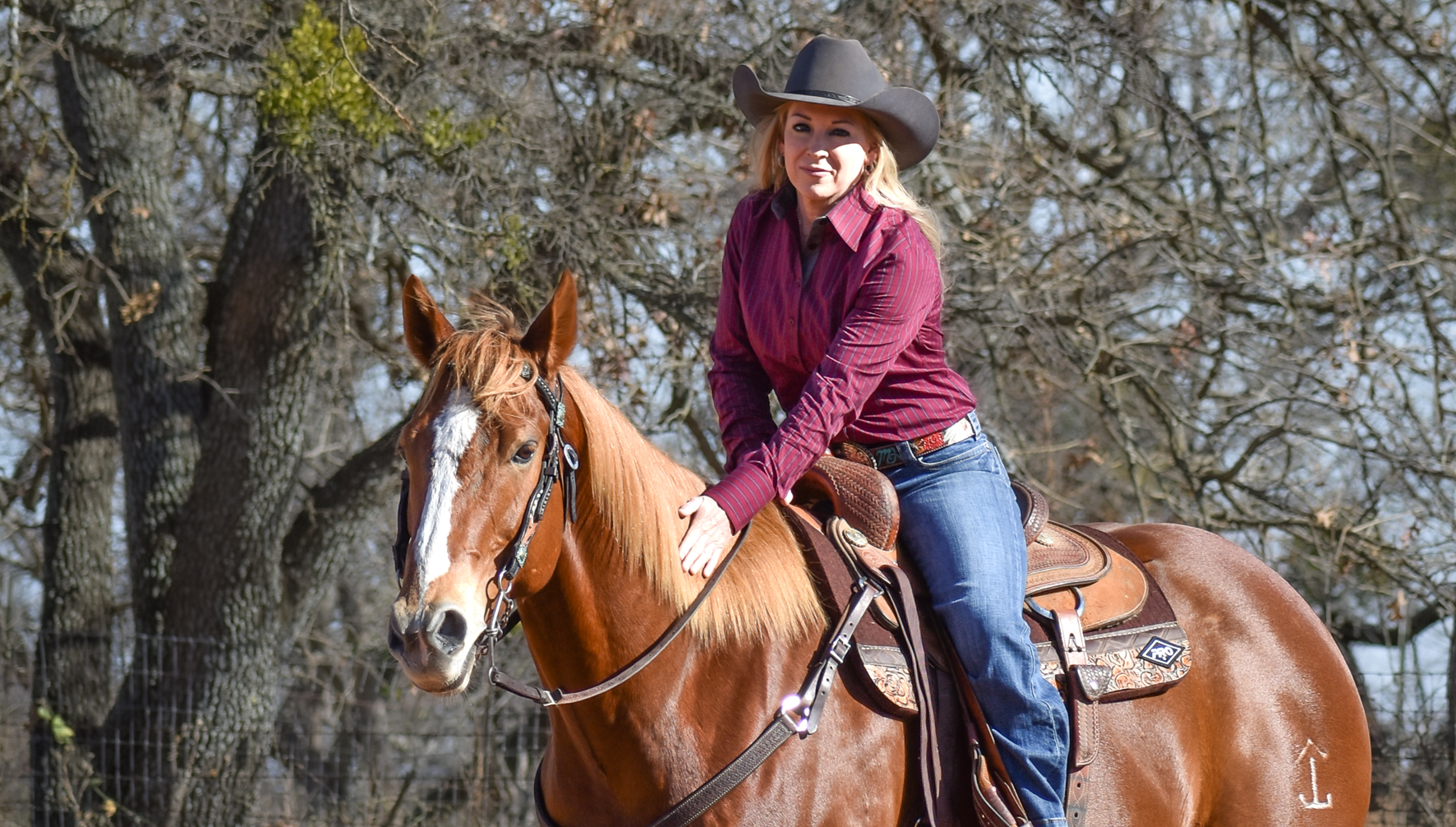 Woman riding a brown horse with trees in the background